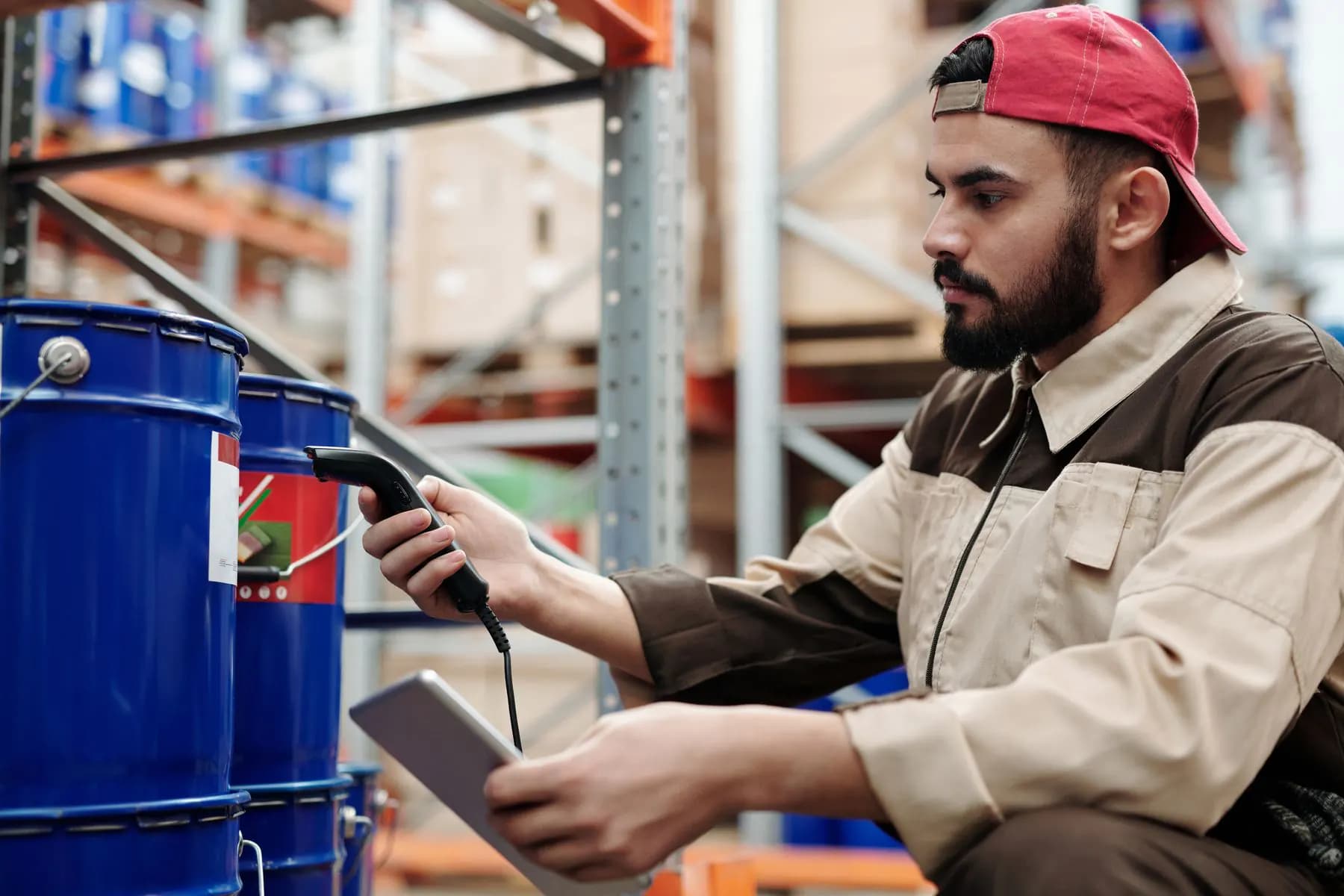 A warehouse worker checking stock levels on a tablet beside the shelves