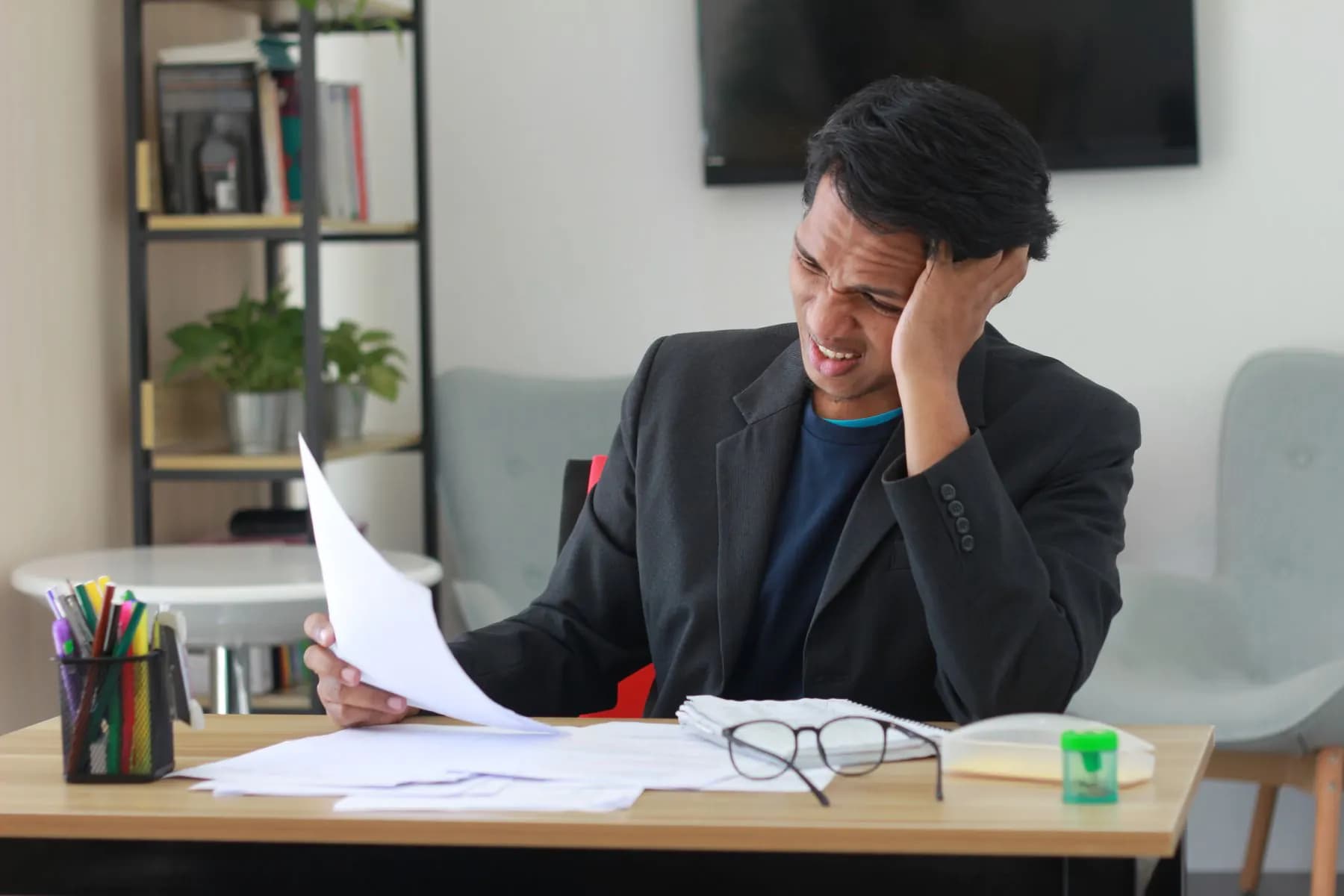 A business owner at a desk, buried in printed reports and spreadsheets