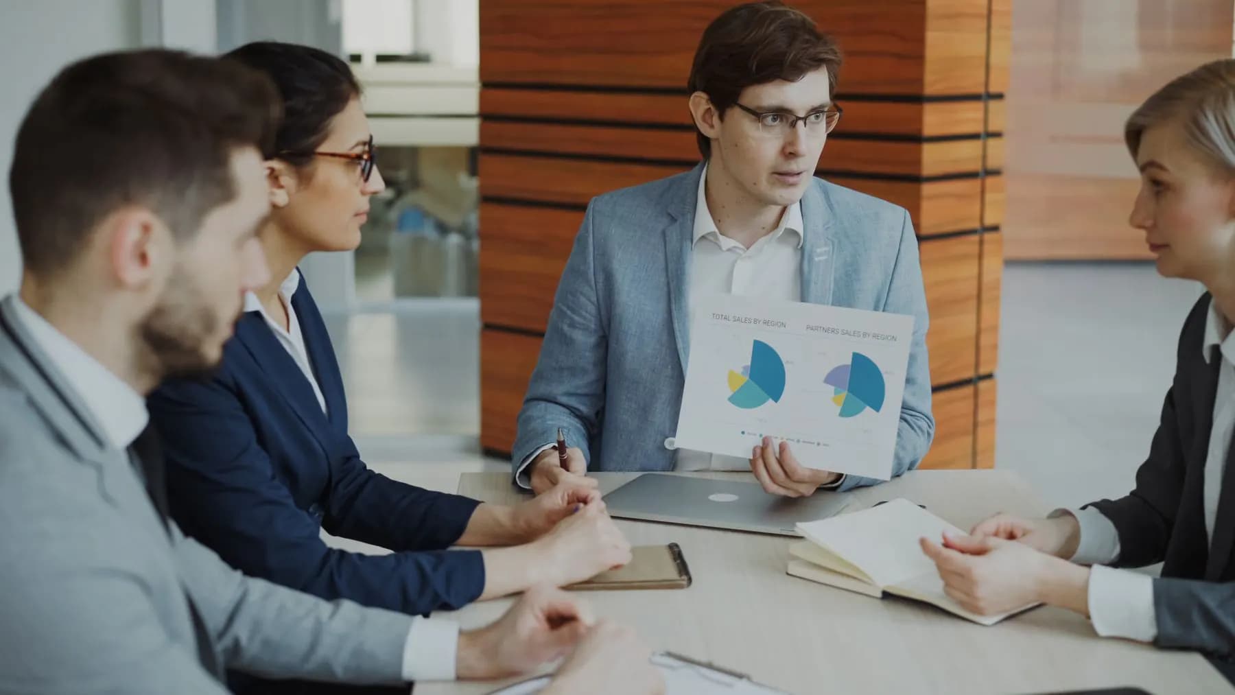 A sales team reviewing charts and customer reports around a table