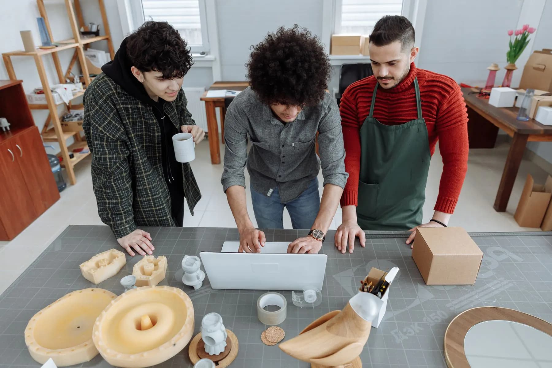 A small workshop team working out a process together around a laptop