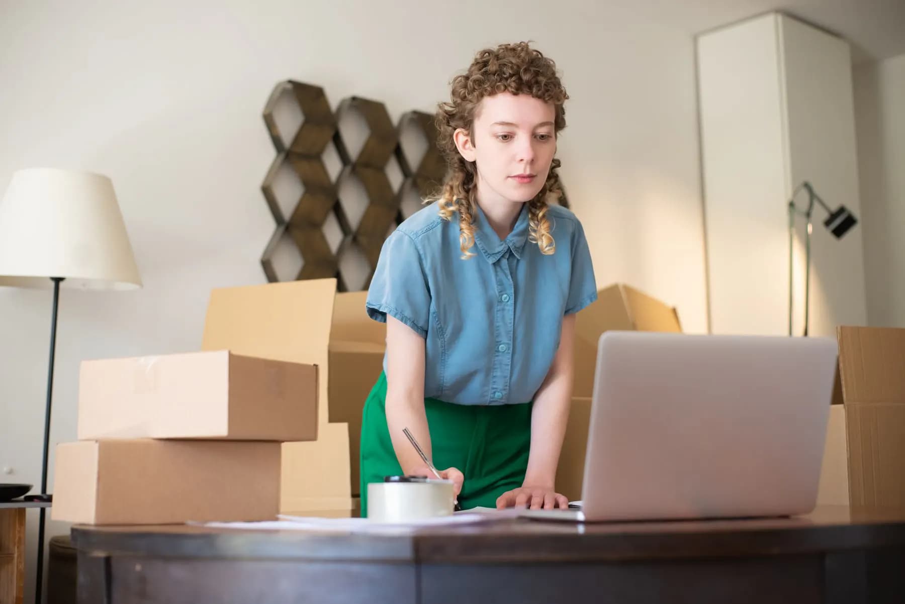 An online seller working on a laptop between packed parcels