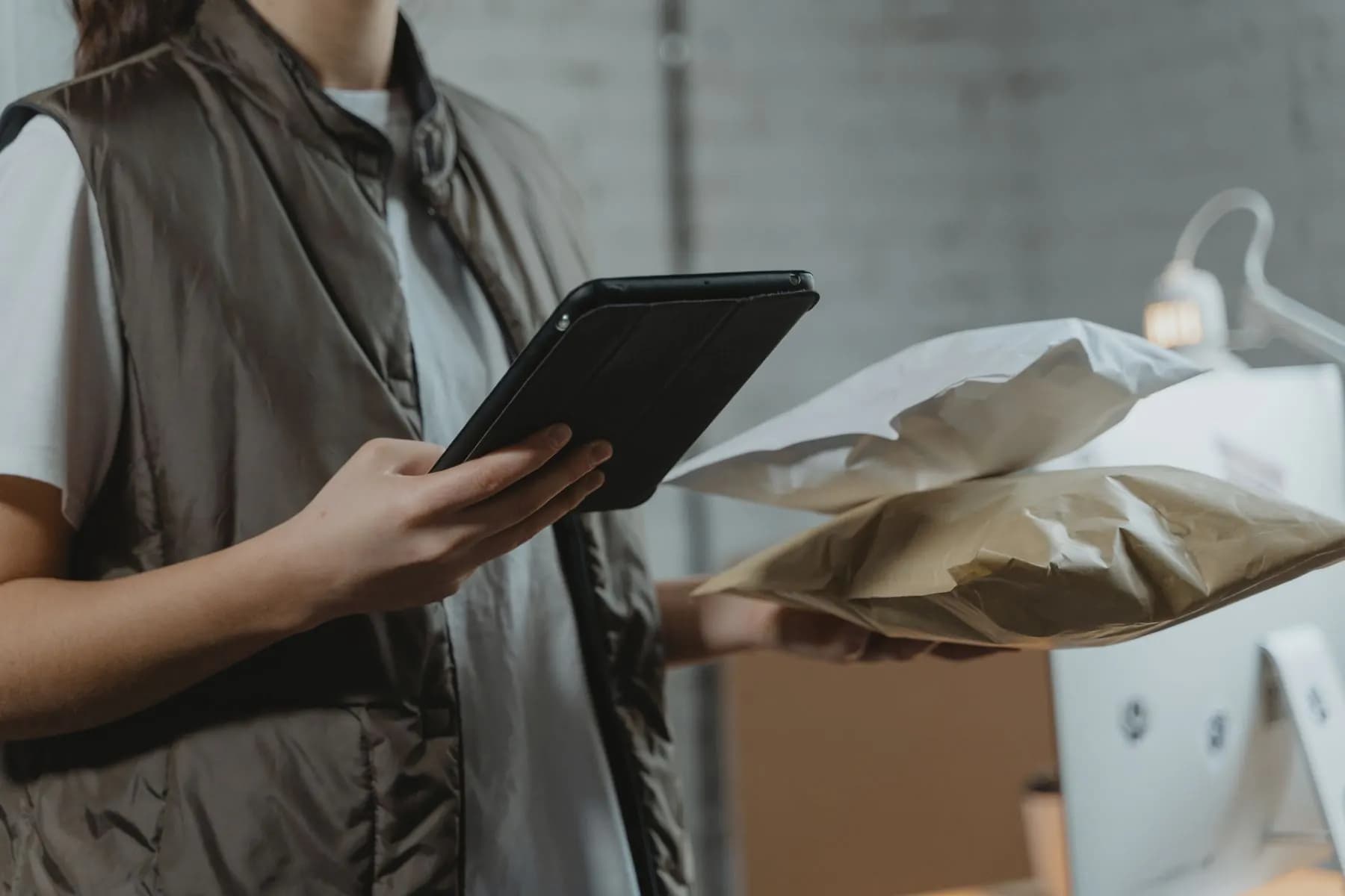 A shop owner checking orders on a tablet among packed parcels