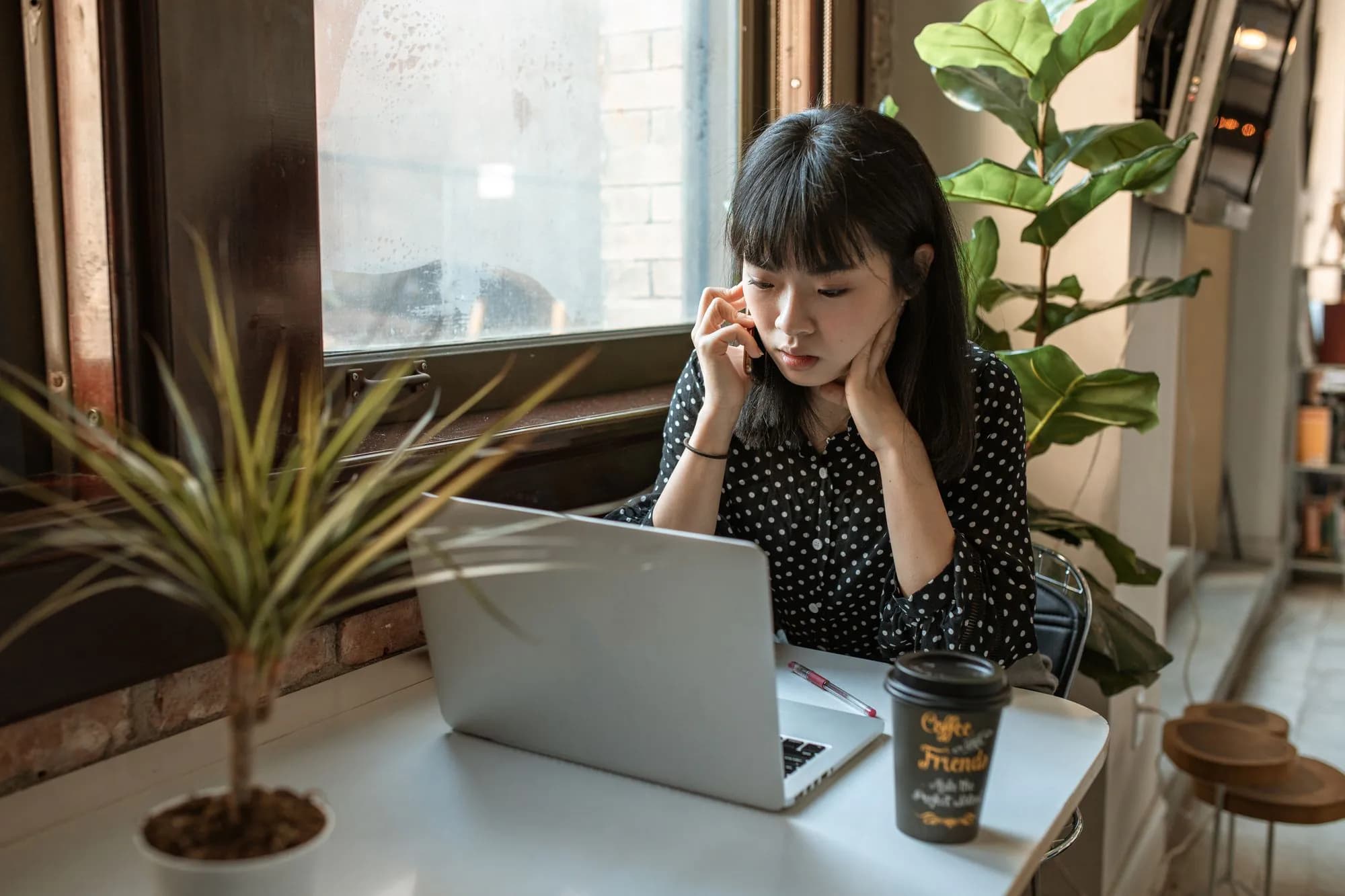 A woman on the phone at her laptop in a bright office