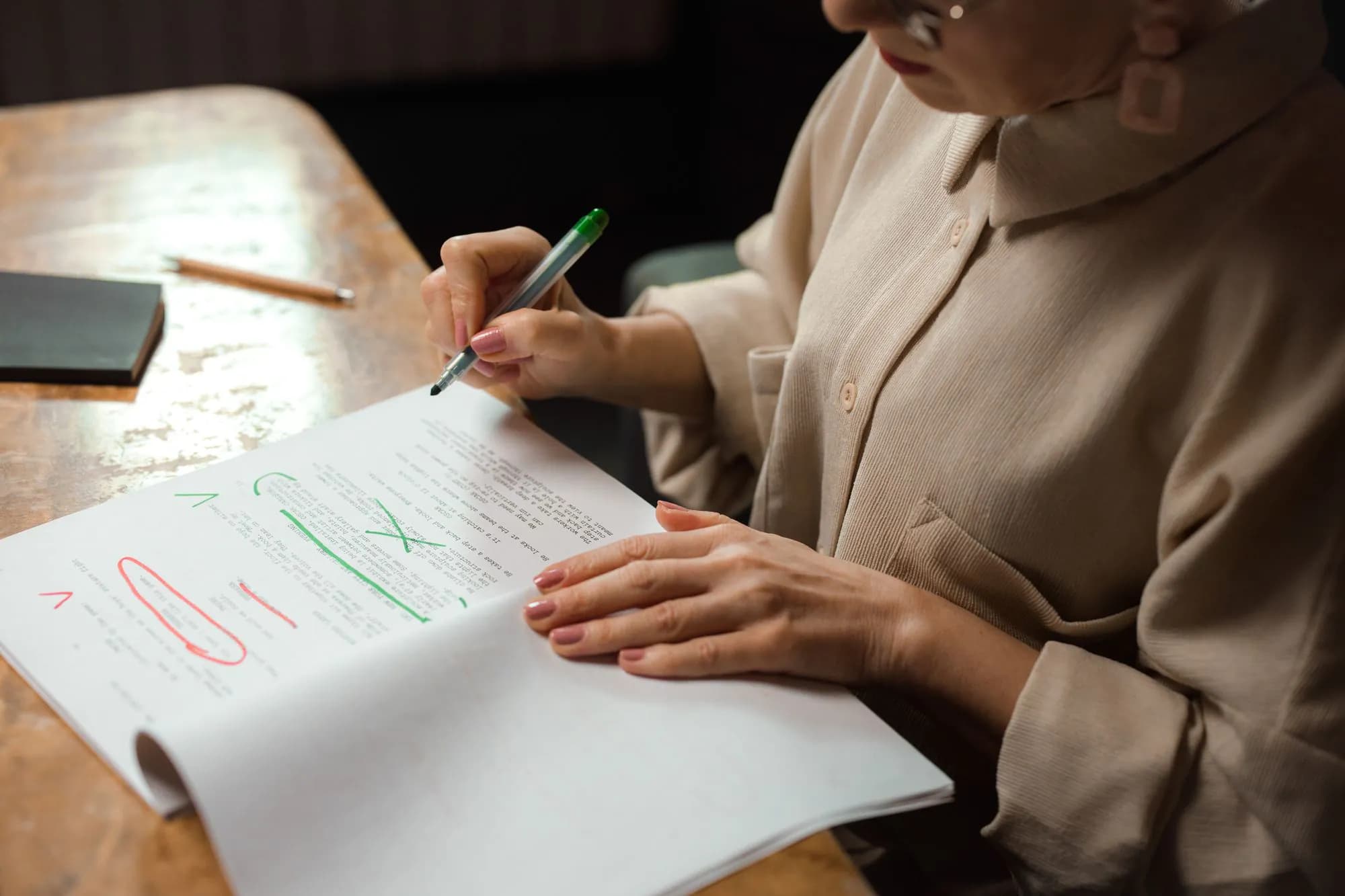 A woman editing a printed text with a green marker