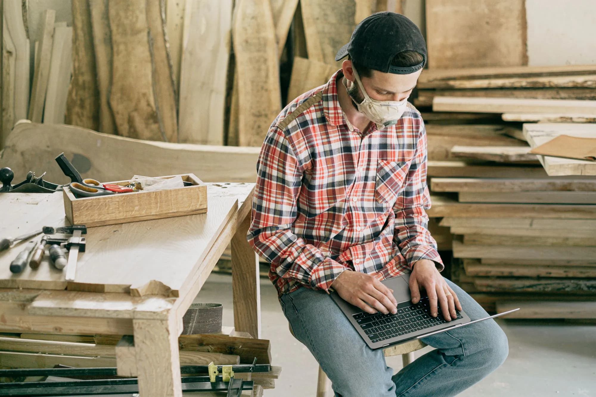 A craftsman in his workshop working on a laptop