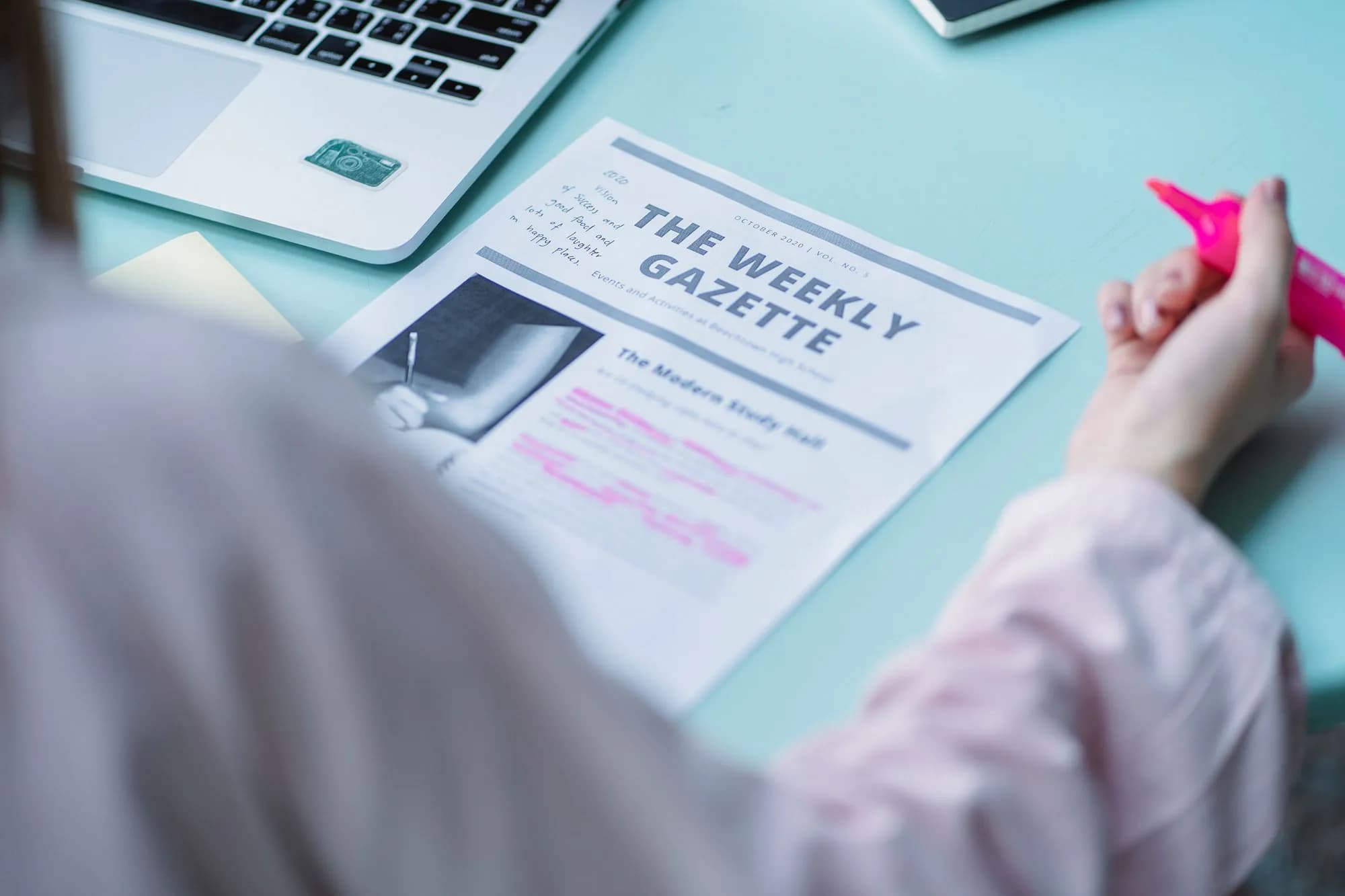 A person reading a printed newsletter with a marker in hand