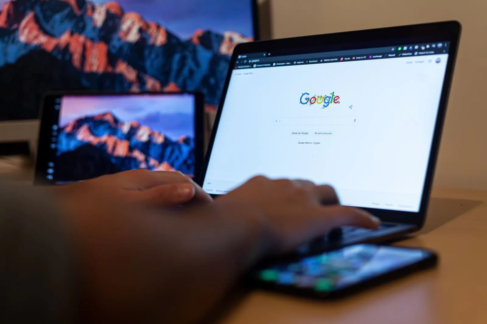 Someone searching on Google on a laptop, a phone beside it