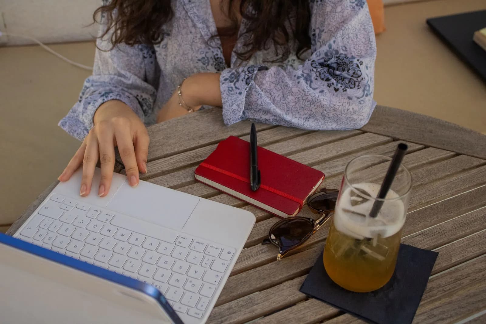 A woman writing a page on her laptop at a café table