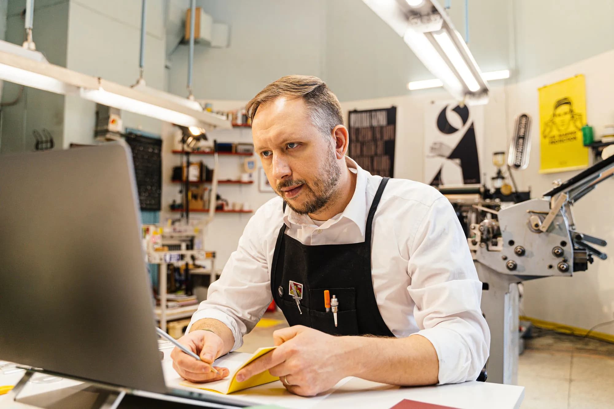 A print shop owner working at his computer in his busy workshop