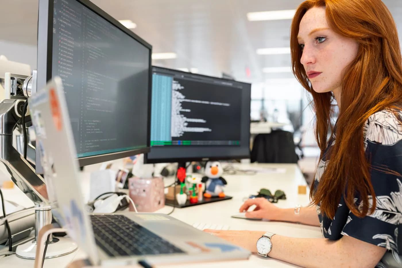 A web engineer working across two monitors in a bright office
