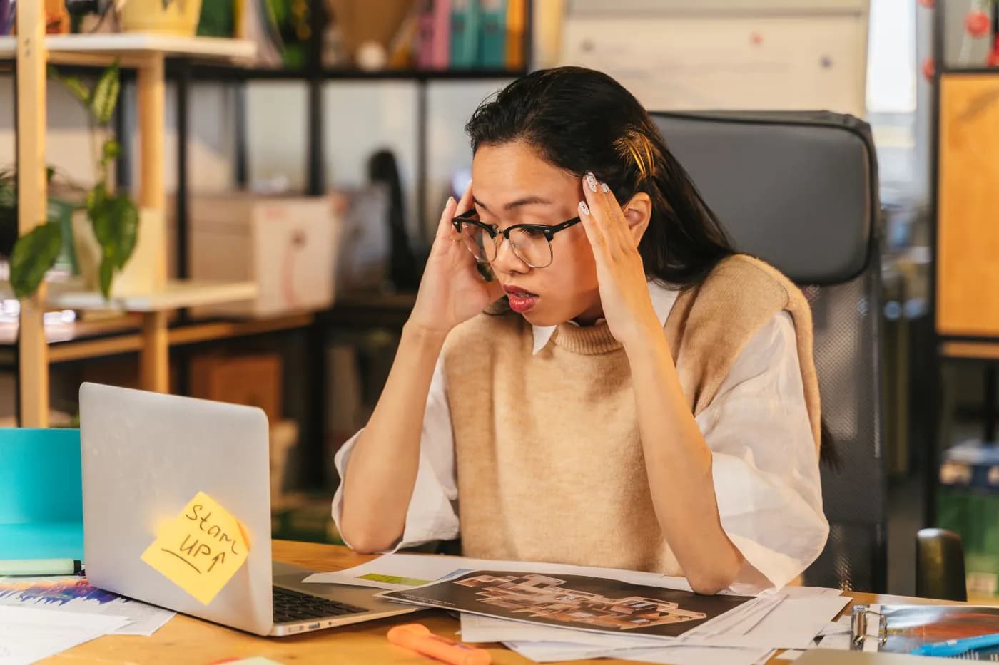 A business owner with her head in her hands at her laptop